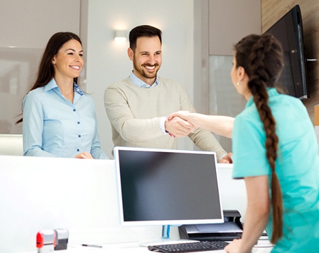 Dental patient shaking hands with dental office employee