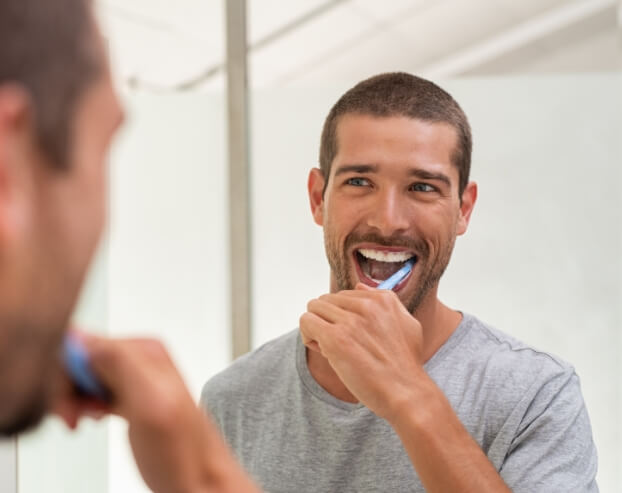 Man brushing teeth after dental bonding treatment