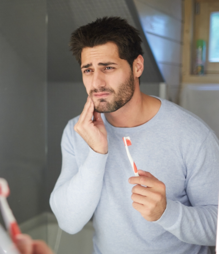 Man in need of emergency dentistry holding jaw in pain