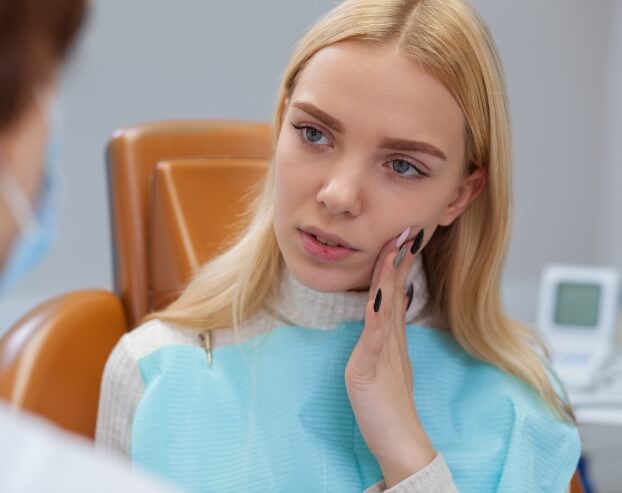 Woman holding jaw in pain before tooth extraction