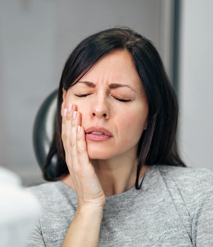 Woman in need of gum disease therapy holding cheek in pain