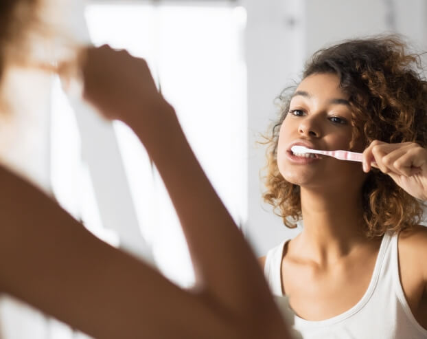 WOman brushing teeth to prevent gum disease