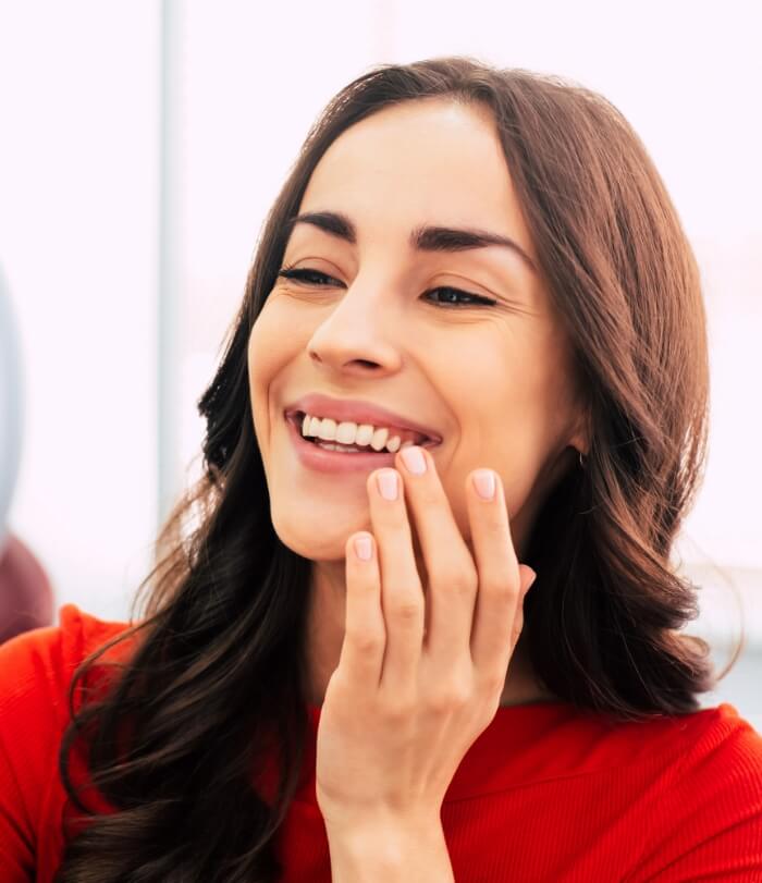 Woman looking at smile after tooth replacement with dental implants