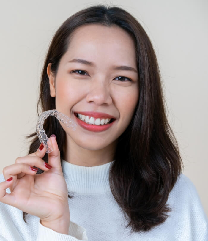 Smiling woman holding an Invisalign tray