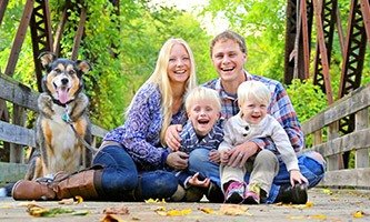 Smiling family of four with dog outdoors