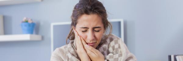 woman holding her jaw in pain