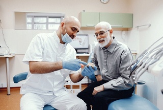 Dentist talking to senior gentleman about dentures