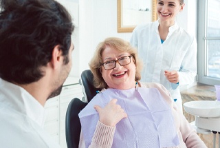Woman smiling in treatment chair at dental team