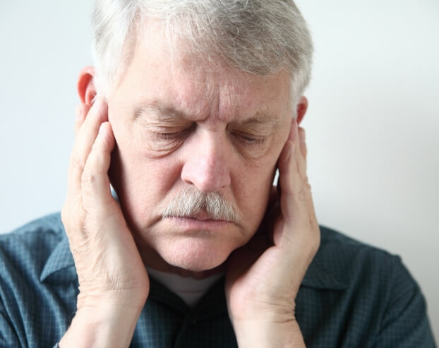 Man in need of T M J therapy holding jaw in pain