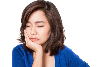 A woman holding her cheek and jaw in pain