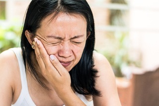 A woman holding her cheek in pain