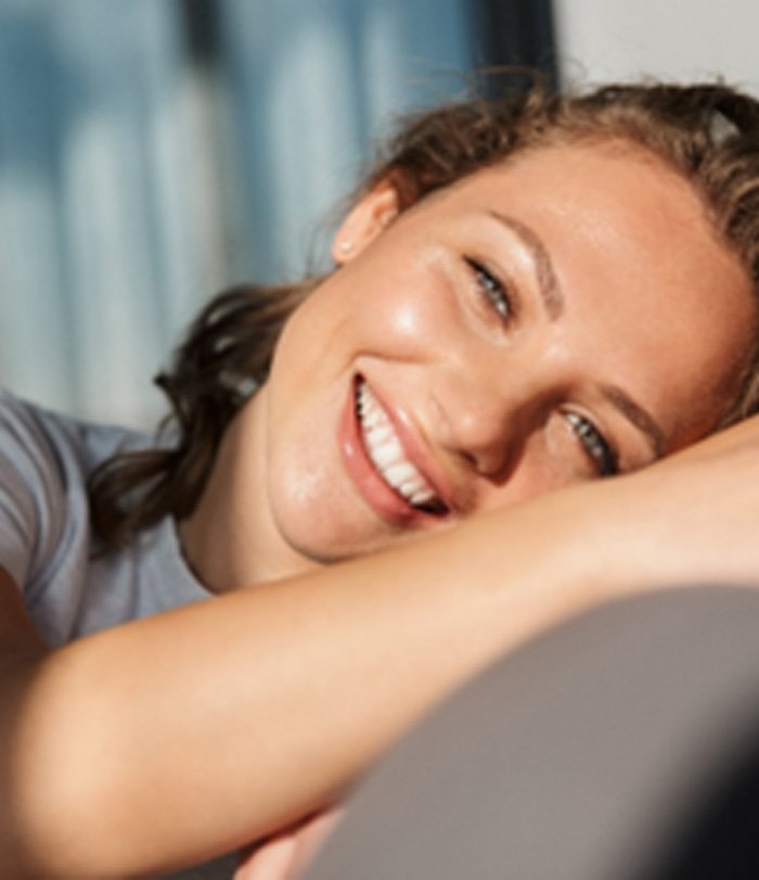 Smiling woman with white teeth relaxing on couch