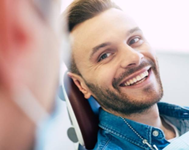 Man in denim shirt smiling at Boston cosmetic dentist